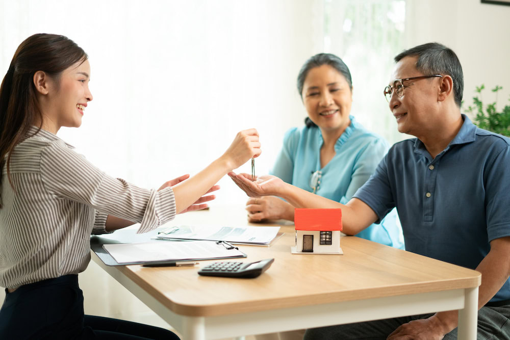 An expat couple receives the keys from a lawyer for buying a house in Thailand as a foreigner.